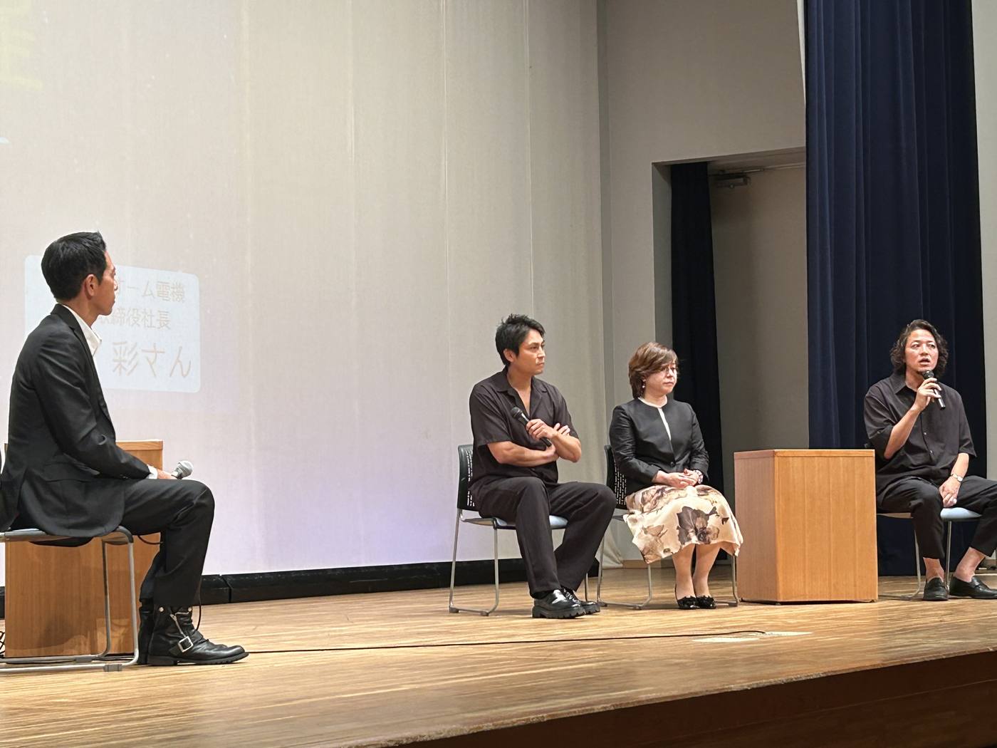 ステージ上で椅子に座り、マイクを持って話す監督・寿大聡とトークショーの登壇者たち